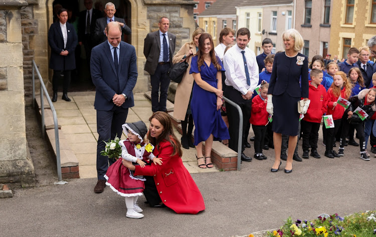 Britain's Princess of Wales embraces two-year-old Charlotte Bunting next to Prince William during a visit to St Thomas Church in Swansea.