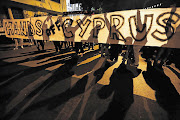 Anti-Troika protesters hold a 'Hands off Cyprus' banner during a demonstration outside the EU offices in Nicosia, Cyprus capital, yesterday. Today is the deadline for Cyprus to avert a collapse of its banking system and accept the EU bailout terms