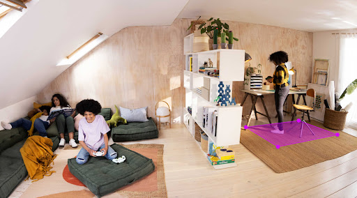 A teenager is seen at their parent's computer in a home office area, as other family members are nearby.