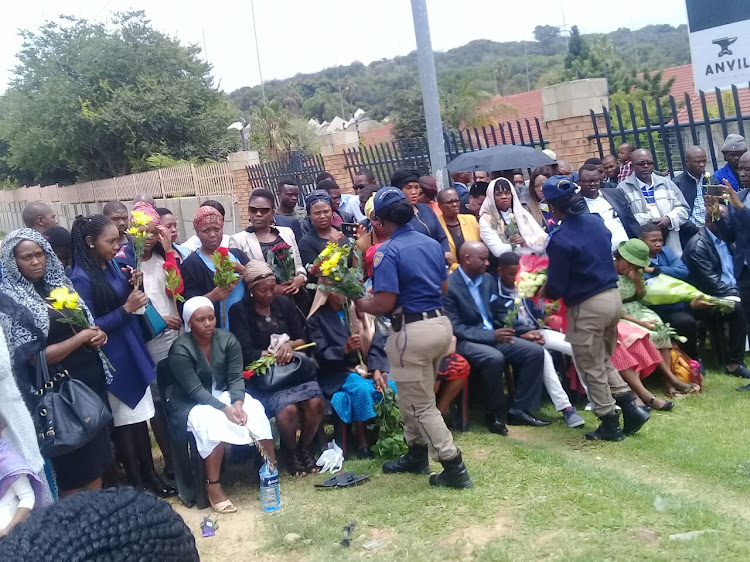 JMPD officers hand flowers to the families of the deceased officers.