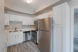 Kitchen with pantry cabinet, stainless steel appliances, white shaker cabinets, brushed nickel hardware, and plank floors