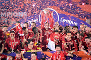 Jordan Henderson of Liverpool holds the Premier League Trophy aloft along side Mohamed Salah as they celebrate winning the League during the presentation ceremony of the Premier League match between Liverpool FC and Chelsea FC at Anfield on July 22, 2020 in Liverpool, England. 