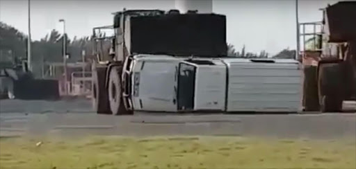 Bulldozers flip a police van.