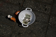 A bowl filled with spare change sits by a man panhandling  at Times Square in New York City, US, June 7, 2021. 