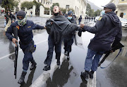 Police grab a demonstrator in front of parliament in Cape Town on August 29 2020.