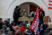 A mob of supporters of then-U.S. President Donald Trump climb through a window they broke as they storm the U.S. Capitol Building in Washington, U.S.on January 6, 2021.