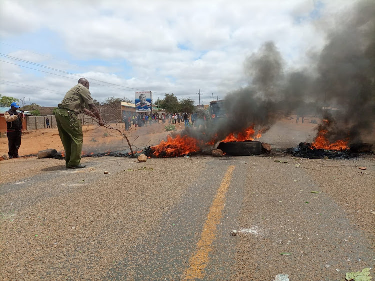 Afisa wa polisi akisafisha barabara ya Kyuso-Mwingi iliyofungwa kwenye daraja la Kamuwongo kaunti ya Kitui Jumatatu.