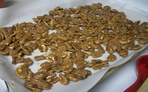 Glazed pecans on baking sheet lined with parchment paper.