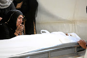 Sakina Essop,  the widow of Abbas Essop,  grieves at her husband's side before the burial. 