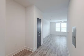 Apartment entry way with wood plank flooring, a closet with a navy door, and white walls and trim 