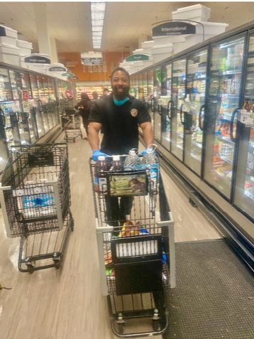 Man in grocery store pushing shopping cart and smiling