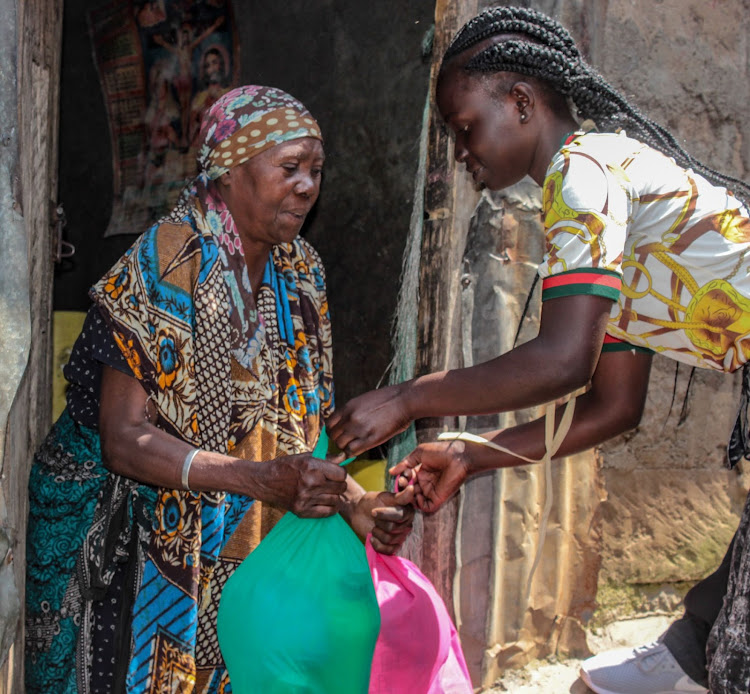 Omtilla Aoko receives food aid from Maureen Auma