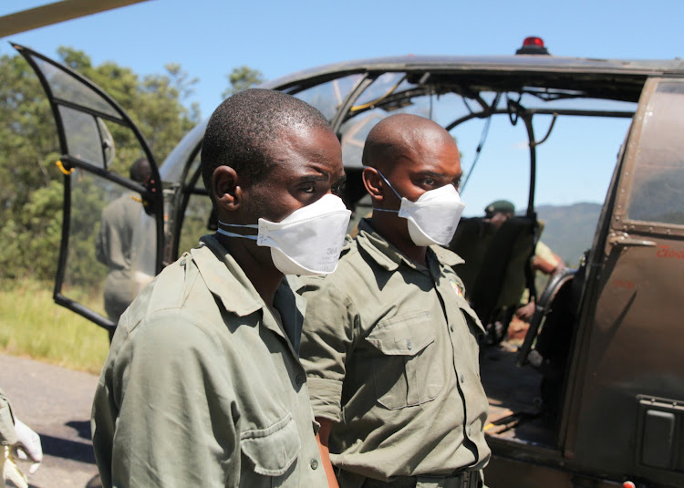 Members of a rescue team wear masks as they prepare to offload a body retrieved from areas flooded in the aftermath of Cyclone Idai in Chimanimani, Zimbabwe, on March 21, 2019