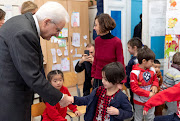 Italian President Sergio Mattarella shakes hands with a child from the 