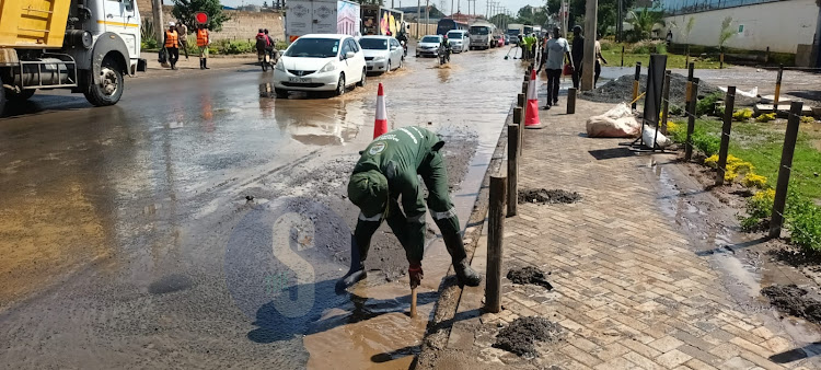 A City Council worker unclogs a blocked manhole in an effort to clear stagnant water along Lungalunga, Industrial area Nairobi on March 25, 2024