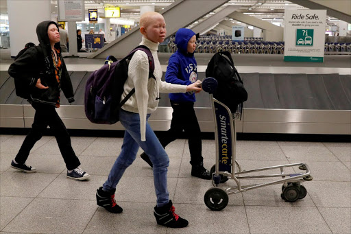 Emmanuel Rutema, Pendo Noni, and Mwigulu Magesa (L to R), Tanzanians with Albinism visiting the U.S. for medical care, walk through JFK International Airport after arriving in New York City, U.S., March 25, 2017. REUTERS/Brendan McDermid