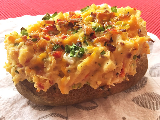 Baked potatoes with filling sitting on a white napkin.