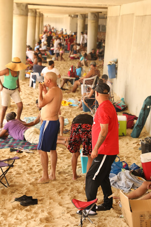 People fill the beachfront, many not wearing masks or adhering to social distancing rules. Some were drinking illegally in public