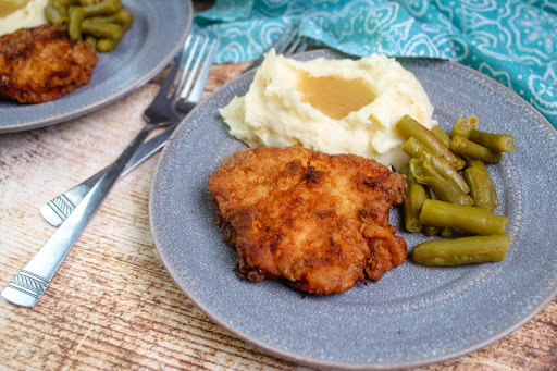 Crispy Southern Fried Pork Chops on a plate with mashed potatoes and green beans.