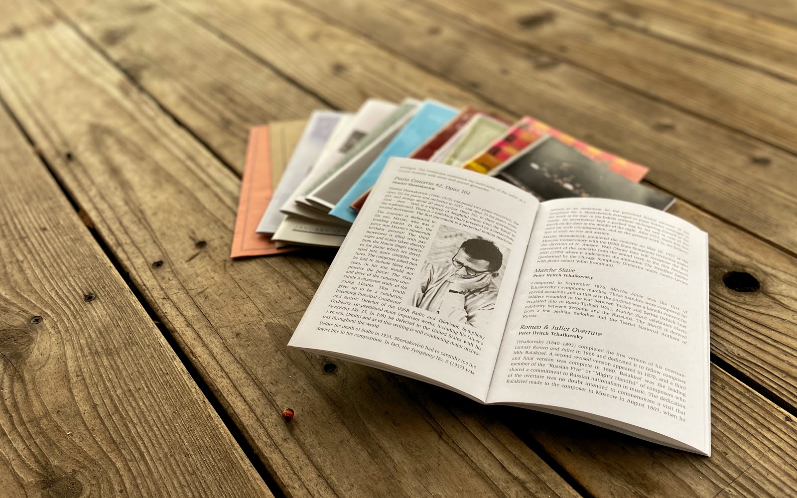 An open concert program on top of stacked programs on a wooden surface