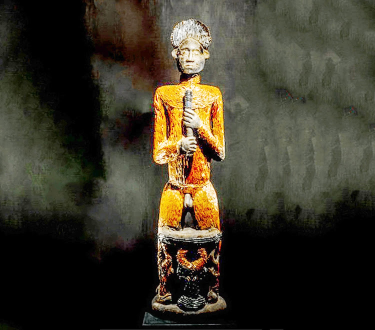 The revered symbol of the Kom people is a 159-centimetre carved wooden statue. It depicts a man standing behind a small throne, wearing a crown and holding a sceptre.