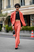 A guest in a black cut-out chest / ribbed pattern / cropped tank-top, an orange blazer jacket, matching orange high waist flared pants outside Fendi, during Paris Fashion Week. 