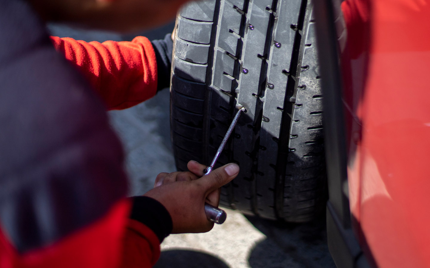 man using tool to pull out nail from tyre