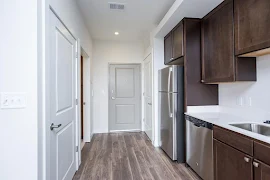 Studio floorplan entryway and kitchen areas with gray exterior door and wood plank flooring