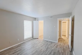 Bedroom with light gray walls, white trim and doors, wood plank floors, and a walk-in closet