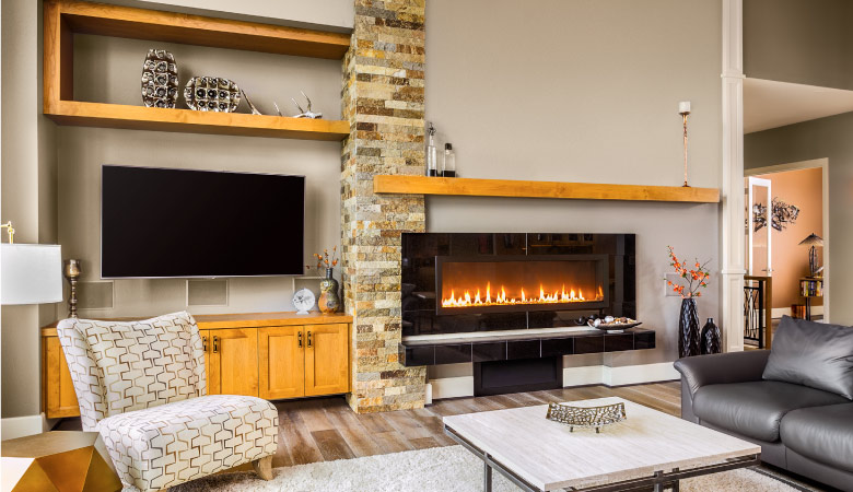 A gas fireplace with black tile surround is emitting a warm glow on a cozy living room.