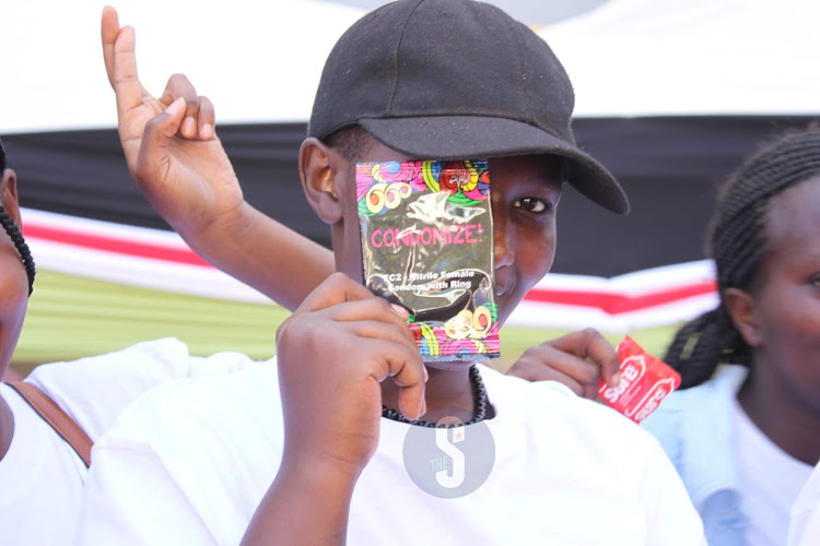 A student shows off a female condom during the International Condom Day at Mount Kenya University Thika on Monday, February 13, 2023.