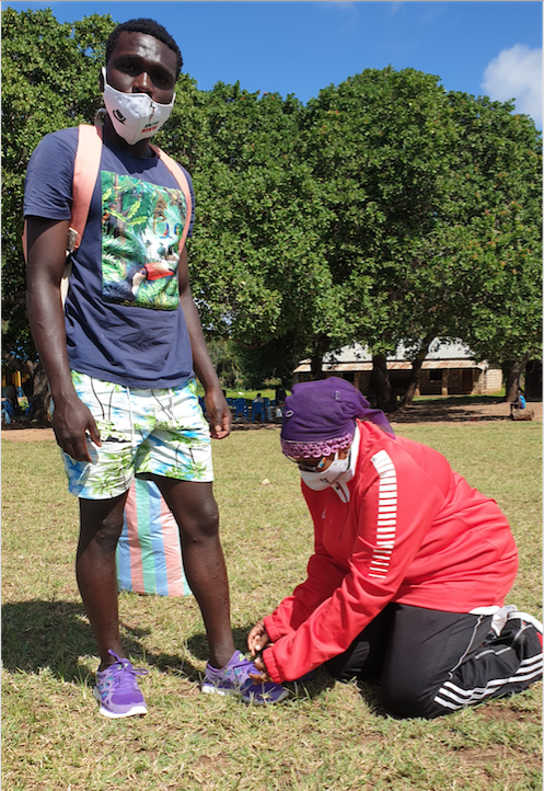 Athletics Kenya Mombasa County chairperson Anisa Abdallah helps sprinter Benson Kombe tie his running shoes at Coast Region Kijiwetanga camp for the World Under-20 Championships at Kijiwetanga Primary School, Malindi, Kilifi County.