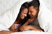 Couple Relaxing In Bed Hiding Under Duvet.