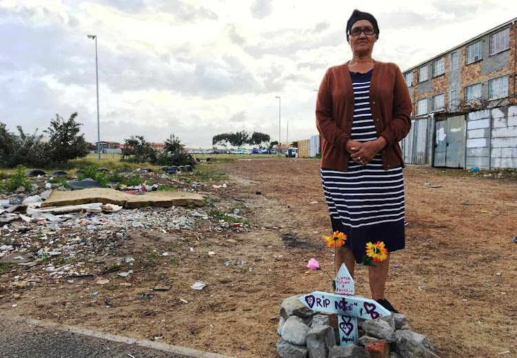 Patricia Swartz at the spot where her daughter Berenice Noble was shot dead two weeks ago in Lavender Hill, Cape Town. Her grandson was also killed in gang violence on Monday. In the distance behind her, people queue to vote at Hillwood Primary School.