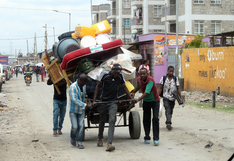 A tent uses a handcart to move her household items after being evicted from her house in Mukuru slums, Nairobi on November 15, 2021