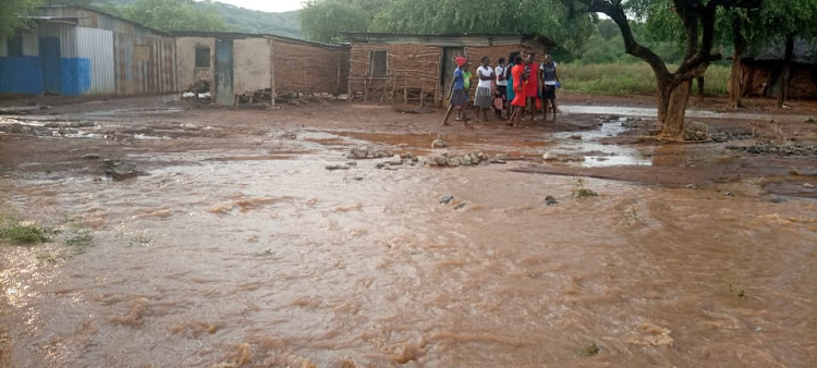 Residents of Tangulbei in Tiaty Sub-county wade through floods caused by heavy rains on Tuesday.