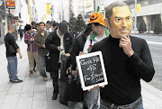 A man wearing a mask of Apple founder Steve Jobs waits to buy an iPhone 4S in Tokyo.