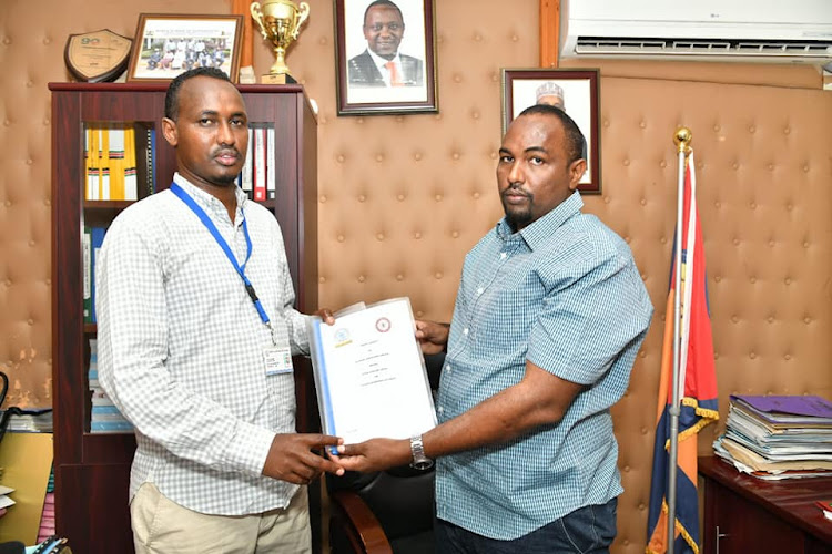 KLB sales and marketing representative, Ali Bille gives Garissa county secretary Abdi Ali the partnership business model after the signing of a deal in which KLB will supply learning materials to Early Childhood Development and Education (ECDE) and the Technical Vocational Education and Training (TVET) on Sunday, February 6.