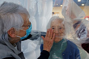 Marie-Paule and Marie-Josephe interact with their mother Colette, 97 years old, behind a removable plastic sheet inside a bubble structure which allows families to give hugs without risk of contamination or transmission of Covid-19, installed in the refectory of the Residence du Carre d'Or retirement home at Jeumont Hospital, as the coronavirus disease outbreak continues in France.