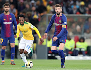 Mamelodi Sundowns' star forward Percy Tau dribbles away from Barcelona's Gerald Pique during the Nelson Mandela Centenary Cup friendly match at FNB Stadium, Johannesburg on May 16 2018.