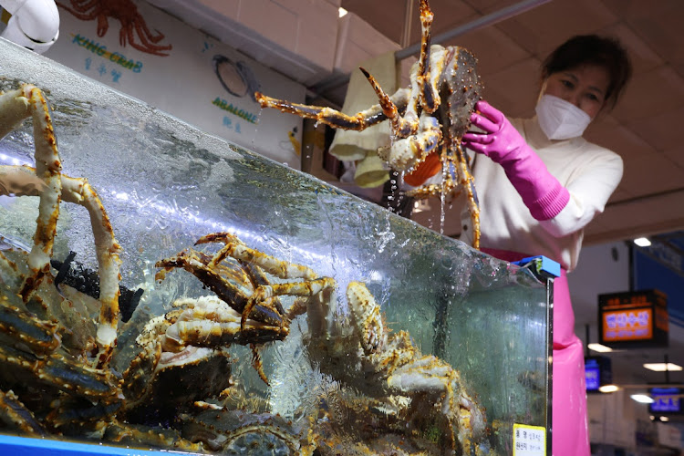 Kim Mi-kyeong, a shopkeeper, shows a king crab imported from Russia to a customer at Noryangjin Fisheries Wholesale Market in Seoul, South Korea, April 8, 2022.