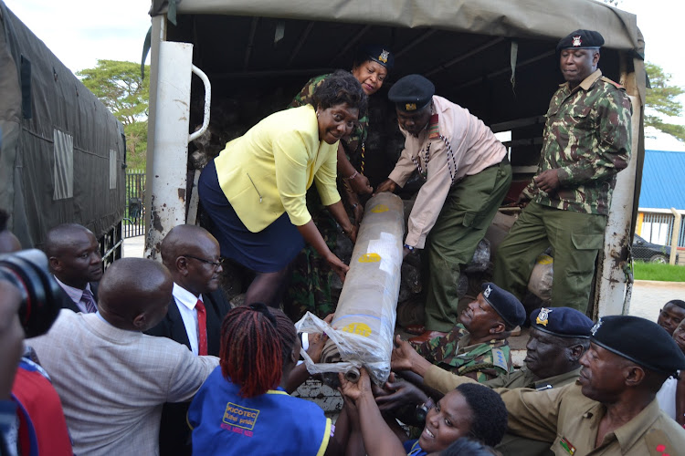 Kitui Governor Charity Ngilu, county police commander Lydia ligami and acting county commissioner Jackson ole Kyuta offload uniform materials on Thursday.