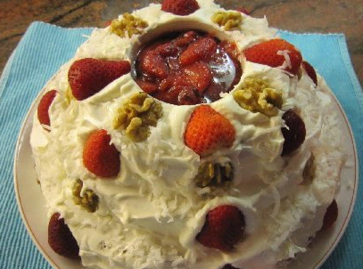 There is a glass in the center of the cake filled with strawberrys and glaze