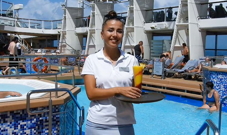 Alexandra, a bar server from Ukraine, serves up a colorful drink on the pool deck of Celebrity Equinox. 