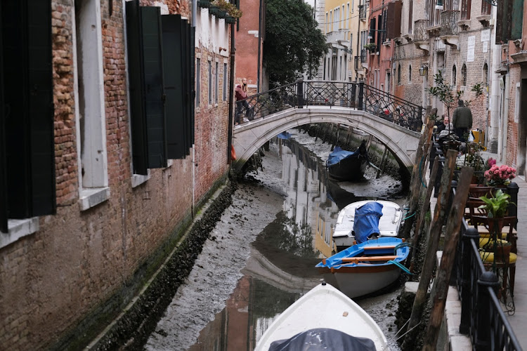 Boats are pictured in a canal during a severe low tide in the lagoon city of Venice, Italy, March 17, 2022.