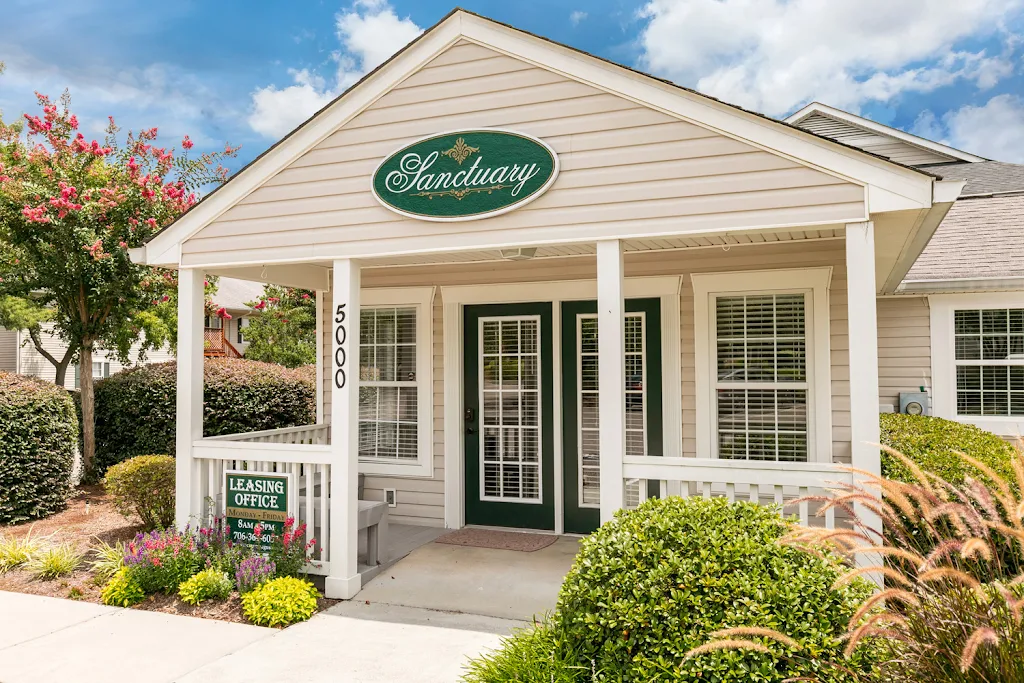 Leasing office entrance with neutral siding, white trim, and landscaping