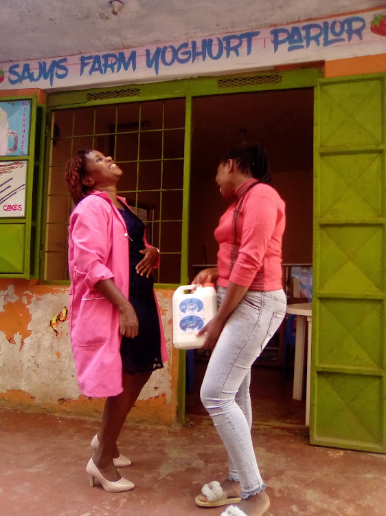 Njeri Wairima shares a light moment with a customer at her Sajys Farm Yoghurt shop located in Ruai, along Kangundo road.