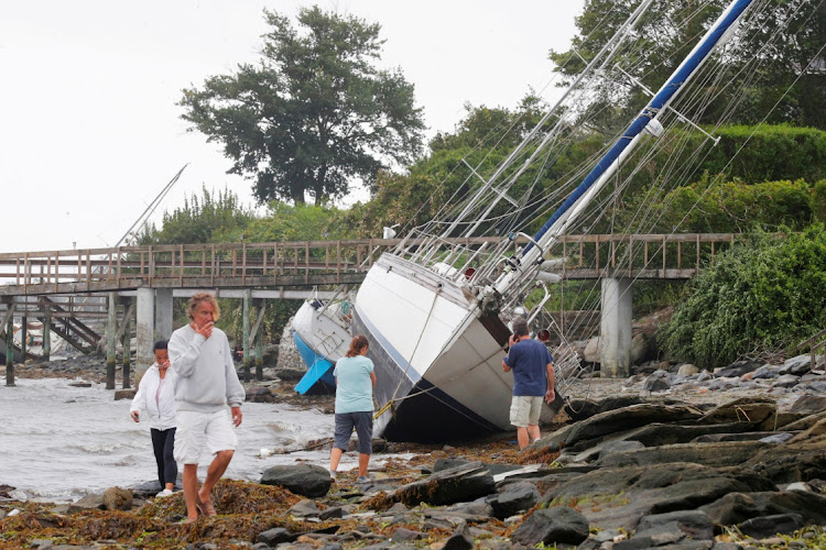 People walk past sailboats that came loose from their moorings and washed ashore during Tropical Storm Henri in Jamestown, Rhode Island, US, August 22, 2021.