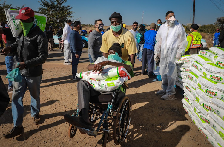 Residents of the informal settlement collect food parcels including maize meal and bread.