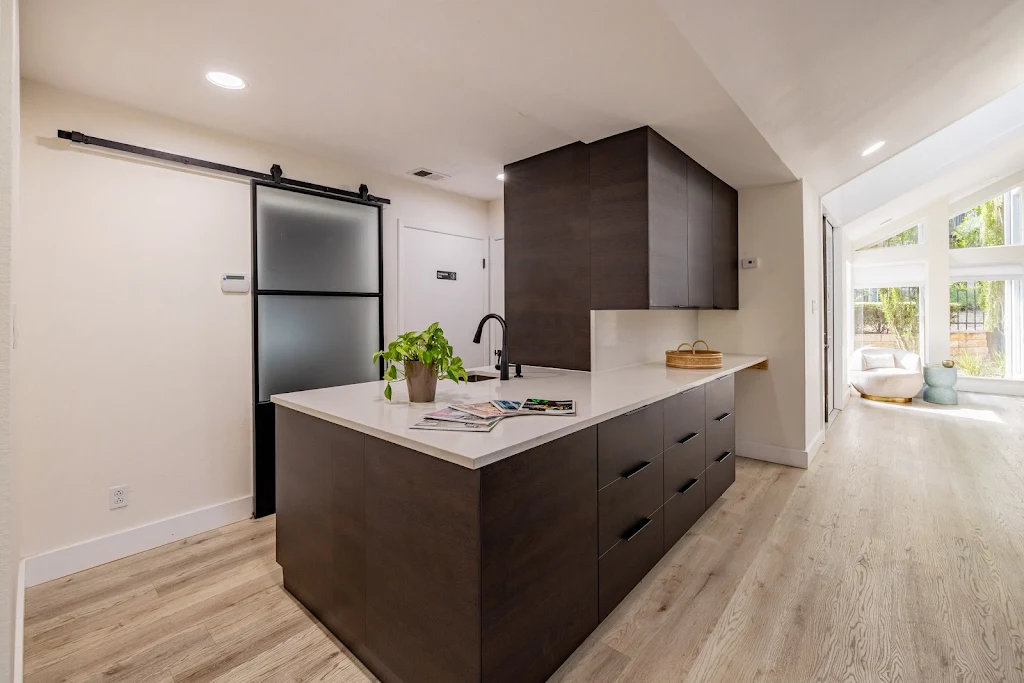 Clubhouse kitchen with black cabinets, white quartz countertop, light wood floors. 